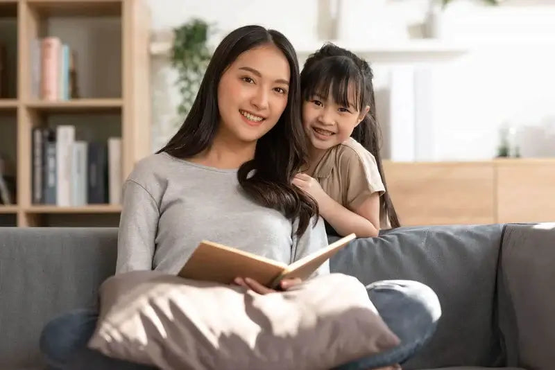 Une mere et sa fille lisant un livre sur le canapé